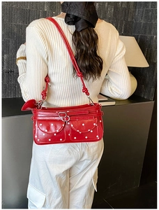 Rear view of a model wearing a red and white polka dot underarm bag with knot strap