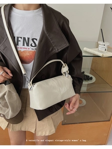 Detail of a cream rectangular handbag with knotted handle and silver metal hardware