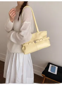 Dettaglio della borsa tote giallo crema con trama in pelle increspata e cinturino fibbia
