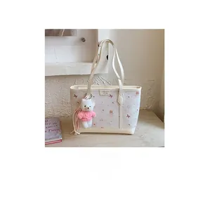 Close-up of a floral canvas tote bag featuring a cute white teddy bear plush charm
