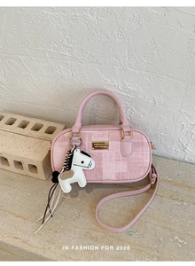 Détail d'un sac à main rose à carreaux avec breloque poney posé sur du marbre