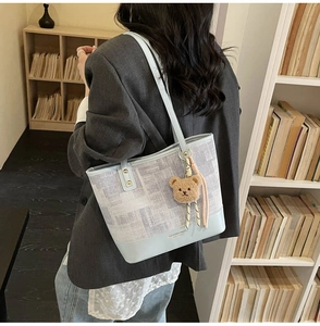 Détail du sac cabas patchwork bleu clair avec imprimé journal et charm ours en peluche