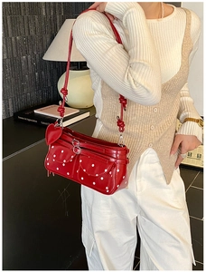 Detail of red polka dot shoulder bag with heart charm shown in a lifestyle setting