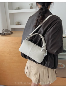 Detail of cream white rectangular handbag with wide strap and silver metal hardware rings