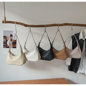 Litchi pattern leather crescent bags in five colors displayed on a natural branch