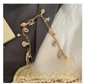 Close-up of beach straw bag with gold chain featuring starfish, shells, and pearls
