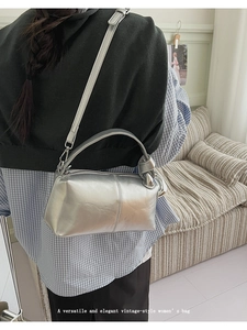 Model view of silver metallic bag with chunky handle and detachable strap on shoulder