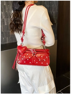 Close-up of red polka dot shoulder bag featuring heart charms and tassel details