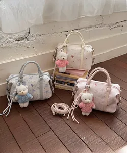 Drei Boston-Taschen aus Leder in Weiß, Blau und Rosa mit Bärenanhängern und Kunstdrucken