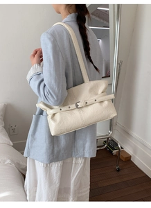 Dettaglio della borsa a spalla in pelle color crema con cinturino su una modella in posa