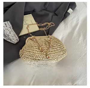 Detail of shell-shaped straw bag featuring gold chain with shell and pearl charms