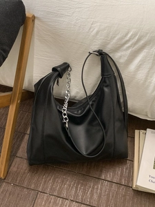 Minimalist black PU leather hobo bag with silver chain strap on wooden floor background