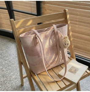 Sac seau en tweed rose avec poignées en cuir et breloque ours sur une chaise
