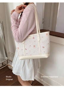 Close-up of cream tote bag featuring cute pink cat and cupcake patterns in faux leather