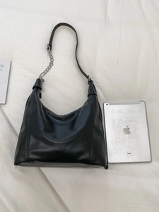 Chic black faux leather hobo tote with silver chain strap next to an iPad for scale
