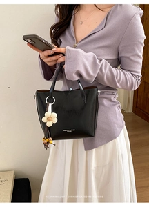 Dettaglio della borsa tote in pelle lucida nera con ciondolo a fiore e perline