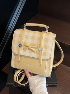 Chic yellow checkered small backpack with a bow and adjustable straps in a lifestyle setting