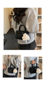Detail of black faux leather handbag with belt buckle and white plush sheep charm