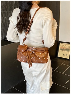 Close-up of brown polka dot shoulder bag with heart charm and metal buckle details