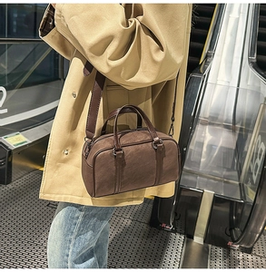 Detail of dark brown matte Boston bag with top handles and adjustable shoulder strap