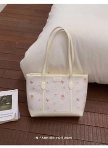 Close-up of quilted white tote bag with cute pink bear patterns and leather brand label