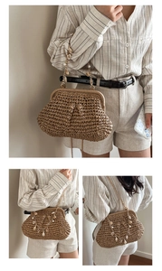Detail of woven straw beach bag featuring seashell and pearl embellished metal chain strap