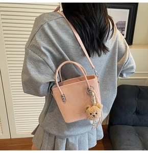 Pink bucket bag with silver beads and plush bear charm shown in a lifestyle setting