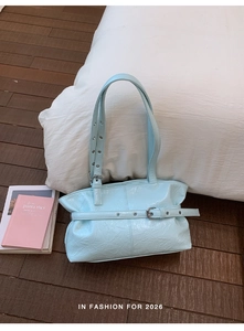 Detail of light blue wrinkled patent leather tote with eyelet straps and silver buckle