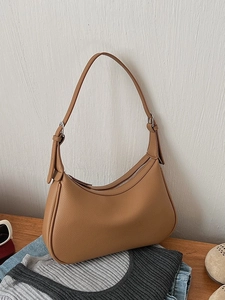 Caramel brown pebbled leather crescent underarm bag with adjustable silver hardware strap