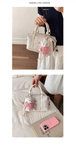 Detail der cremefarbenen Boston-Handtasche mit Blumenstickerei und rosa Teddybär-Anhänger