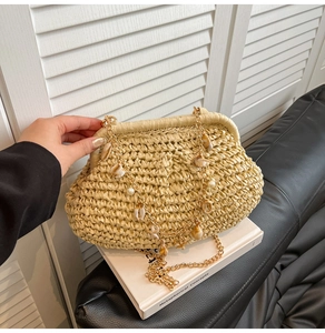 Detail of beige woven straw bag with golden chain, sea shells and white pearl accents