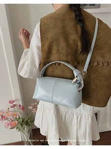 Detail of light blue leather handbag with wide handle and metal side buckle