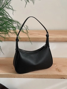 Minimalist black lychee texture underarm bag with adjustable shoulder strap on wooden background