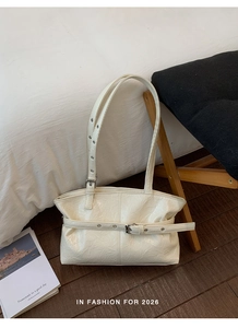 Dettaglio della borsa tote bianco avorio in pelle lucida con fibbia decorativa