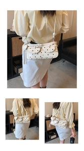 Close-up of white polka dot shoulder bag with flap pockets and heart tassel charm