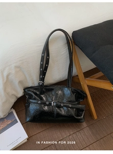 Dettaglio borsa tote in pelle lucida nera con occhielli argento e cinturino fibbia