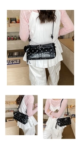 Close-up of black and white polka dot shoulder bag featuring a heart charm and silver buckle