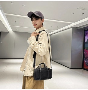 Detail of black cylindrical Boston bag with adjustable shoulder strap on a male model