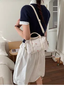 Detail der cremefarbenen Boston-Tasche mit rosa Bärenstickerei und Schleifendetails