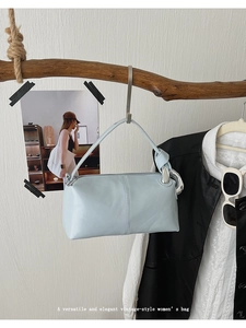Detail of light blue leather baguette bag with knotted handle and silver metal rings