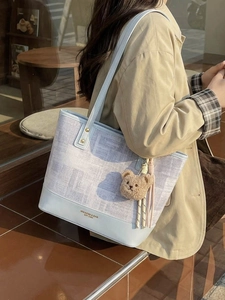 Sac seau bleu clair avec pendentif ours en peluche porté par un mannequin à l'extérieur