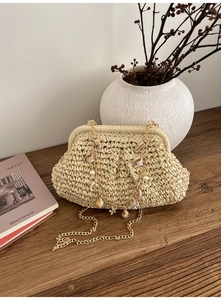 Detail of cream straw beach bag with shell and pearl accents and gold chain strap