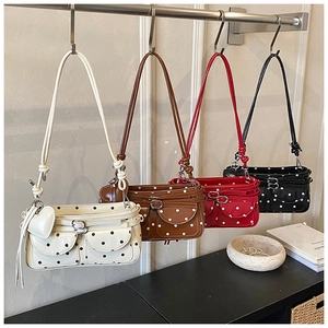 Detail view of retro polka dot underarm bags with front buckle pockets and heart pendants