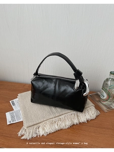 Detail of glossy black patent leather handbag featuring oversized silver metal chain links