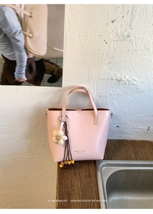 Dettaglio della borsa in pelle rosa con ciondolo floreale e nappa di perline su legno
