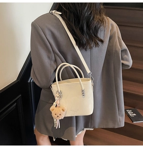 Chic cream white bucket bag with bear charm shown worn by model on stairs