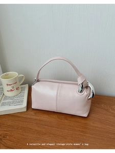 Detail of light pink leather handbag with silver rings on a cozy wooden cafe table