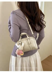 Detail of minimalist cream Boston bag with cute rabbit charm and adjustable strap
