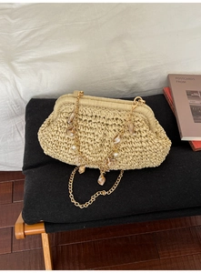 Close-up of beige woven cloud bag featuring gold chain with shells and pearls