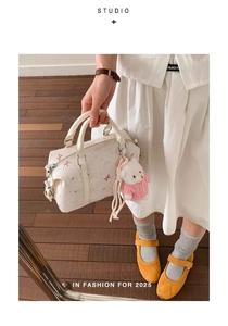 Details der weißen Boston-Tasche mit Sternenprint und süßem Teddybär-Anhänger